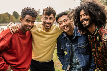 Obraz premium Four happy male friends embracing in a park