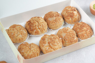 golden brown cream puffs arranged neatly in paper cups. The choux pastries have a crispy outer shell and are ready to be enjoyed as a sweet treat. Ideal for use in bakery catalogs, dessert promotions.