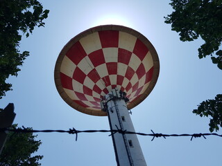 A red and white water tower with barbed wire in the background