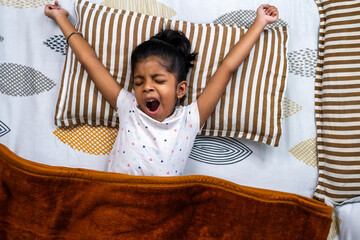 Child waking up and stretching in cozy bed in morning