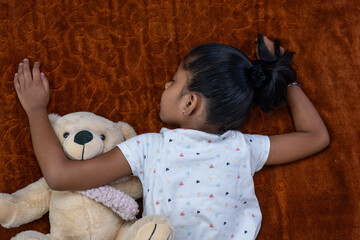 Child sleeping peacefully with teddy bear on cozy blanket
