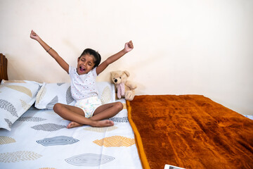 Happy child stretching on bed in cozy bedroom setting