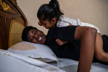 Smiling father enjoys playful moment with daughter at home