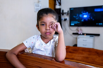 Young girl resting her chin on a wooden railing indoors