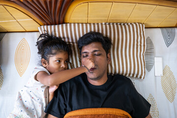 Kid playfully interacting with a sleeping father at home