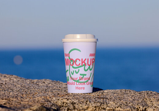 takeaway cup stands on a rocky surface. PSD mockup template