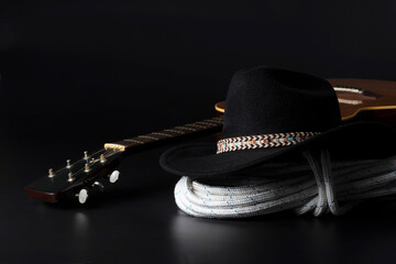Chitarra e cappello da cowboy su sfondo nero con spazio per il testo.
