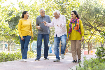 Group of happy indian senior men and women laughing and walking together in summer park. Retirement...