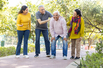 Group of happy indian senior men and women laughing and walking together in summer park. Retirement life, retired people enjoying in garden