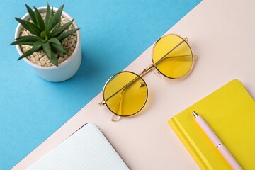 top view of summer workspace with yellow sunglasses and colorful stationery