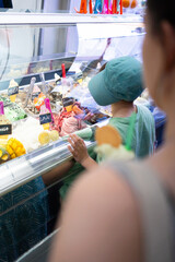 Child choosing ice cream flavor from display case in gelateria