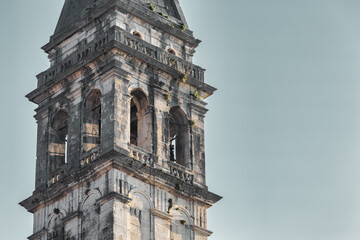 Fototapeta premium Close-up of historic church bell tower in Perast with weathered stone and classical architecture, Montenegro