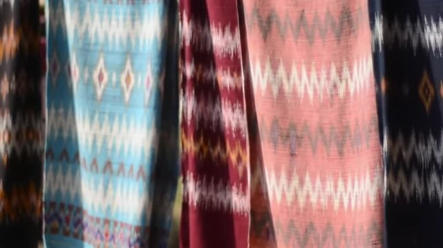 Colorful Sikka ikat weaves catch sunlight as they flutter in silence.