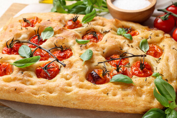 Delicious focaccia with tomatoes and spices on table, closeup
