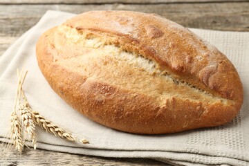 Loaf of bread and spikes on wooden table, closeup