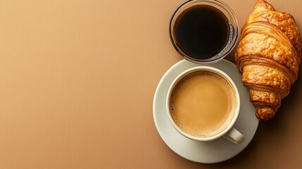 A cup of coffee and a croissant on a brown background. The perfect breakfast or brunch treat!