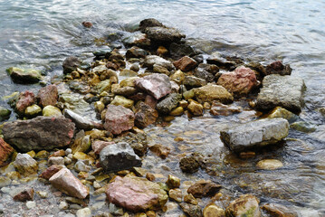 Close Up of Rocks Pebbles and Lapping Clear Water on Lakeside Beach
