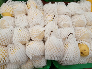 Pears wrapped in foam net are neatly arranged on supermarket shelves for sale
