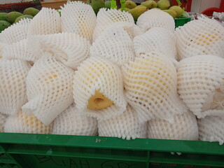 Pears wrapped in foam net are neatly arranged on supermarket shelves for sale