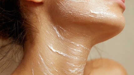 Skincare close up showing woman spreading white moisturizing cream along neck and facial contours, nurturing radiant complexion