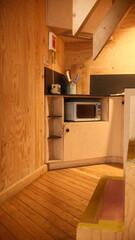 A small room with wood walls and a computer on the floor the scene features  under moody and dramatic conditions.