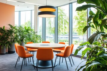 A round table with orange chairs and plants in the corner of an office space, modern in style, with bright interior lighting.
