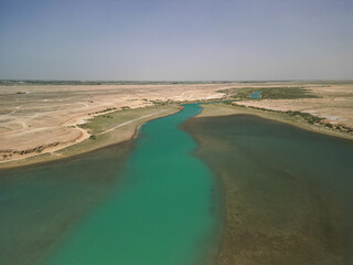 Curving river and green riverbanks between dry plains Kuimazar region Uzbekistan