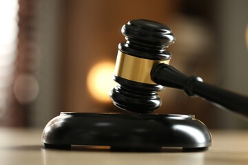 Judge's gavel on wooden table against blurred background, closeup