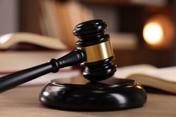 Judge's gavel and books on wooden table indoors, selective focus