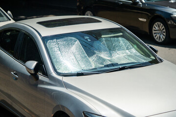 Protective reflective surface under the windshield of passenger car parked on hot day, heated by sun rays inside car. Sunshade, Heat protection, auto accessory concept