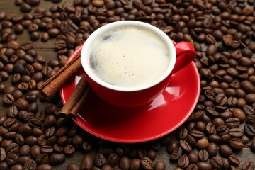 Aromatic coffee in cup, beans and cinnamon on table, above view