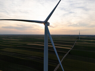 Fototapeta premium Aerial view of wind turbine on an agricultural filed at sunset. Close up of blades