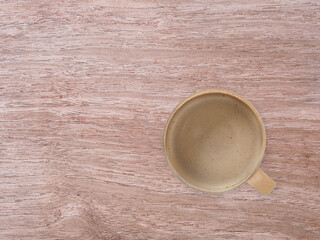 Top view of hot coffee in a brown coffee cup on wooden background, with copy space. Concept for a...