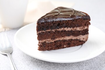 Piece of delicious chocolate cake and fork on grey table, closeup