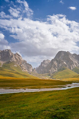 A picturesque view of a river meandering through a wide valley, flanked by grand, rugged mountains...