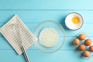 Making whipped cream. Bowl, whisk and ingredients on light blue wooden table, flat lay