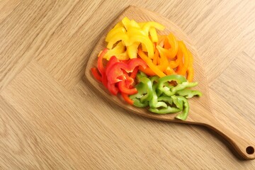 Slices of fresh colorful bell peppers on wooden table, top view. Space for text