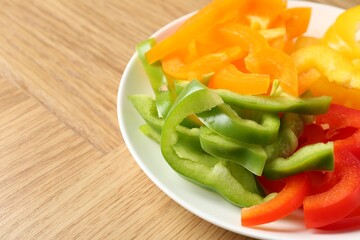 Slices of fresh colorful bell peppers on wooden table, closeup. Space for text
