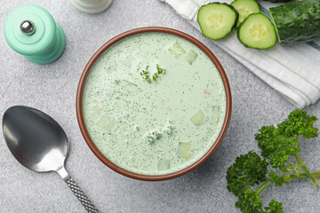 Tasty cucumber soup and ingredients on light grey table, flat lay