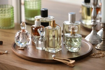 Bottles of different perfumes and accessories on wooden table, closeup