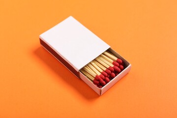 Matches in box on orange background, closeup. Mockup for design