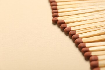 Matches with brown heads on beige background, closeup. Space for text