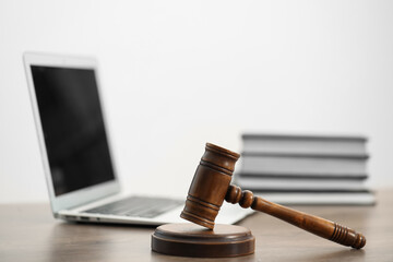 Laptop, judge's gavel and books on wooden table in office, closeup