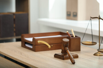 Judge's gavel and scales on wooden table in office