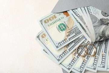 Two gold wedding rings, dollar banknotes and envelope on white table, top view. Space for text