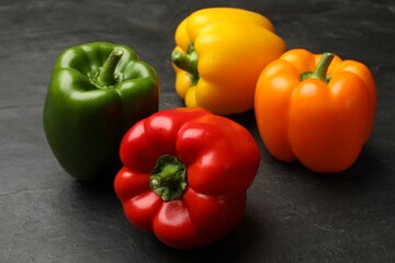 Fresh colorful bell peppers on black textured table, closeup