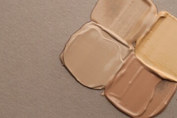 Colorful skin foundations on grey background, flat lay. Space for text
