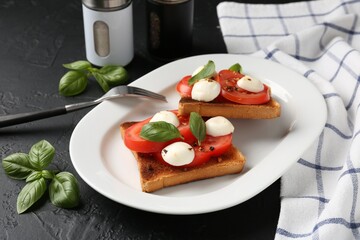 Tasty sandwiches with mozzarella cheese, tomatoes and basil on dark textured table, closeup