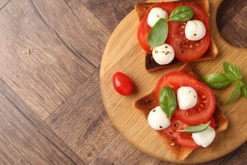 Tasty sandwiches with mozzarella cheese, tomatoes and basil on wooden table, top view. Space for text