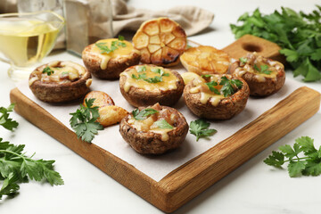 Delicious stuffed mushrooms with melted cheese, garlic and parsley on white table, closeup
